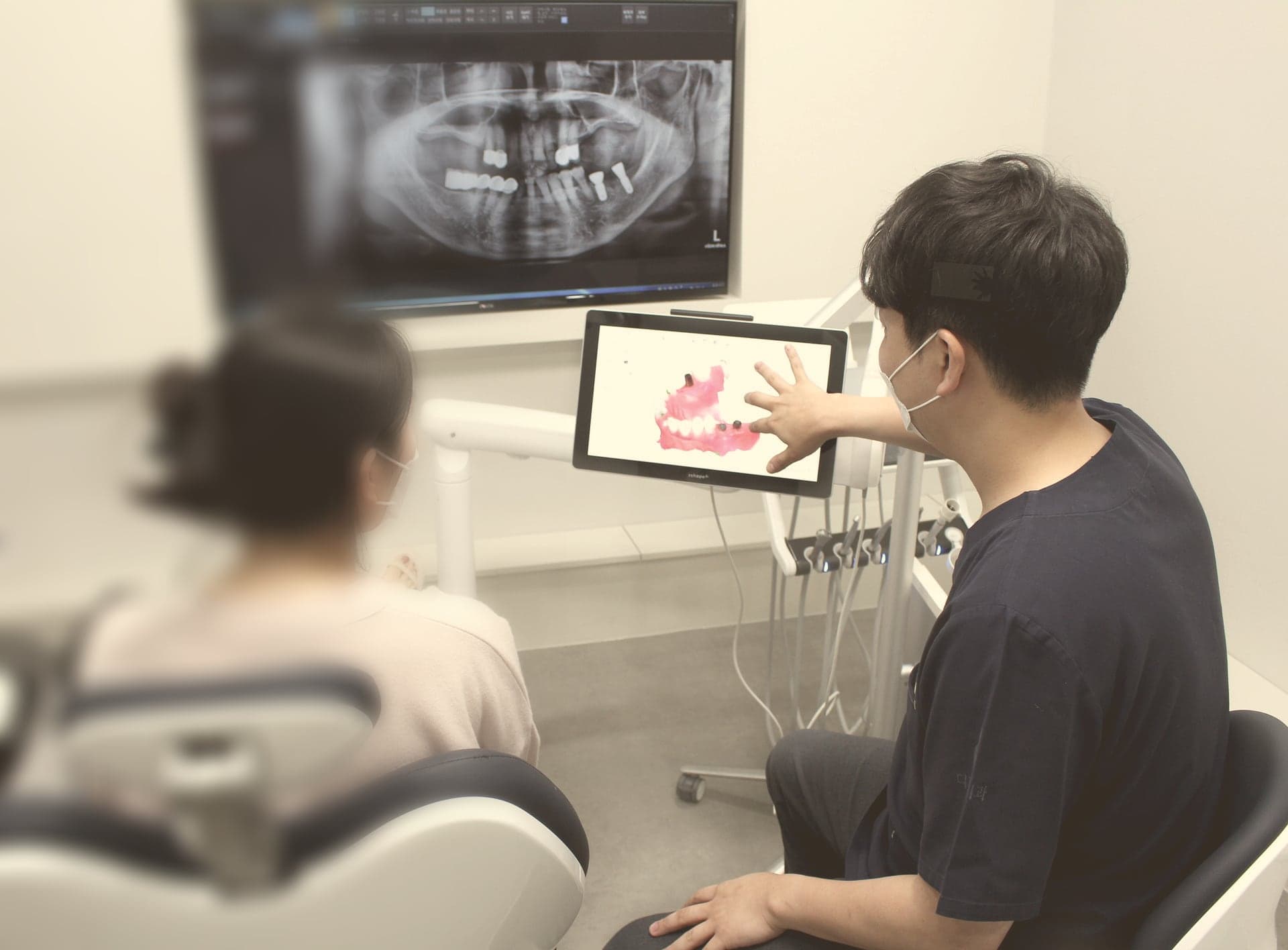 상담실에서 파노라마 엑스레이와 구강 사진을 보며 설명하는 장면