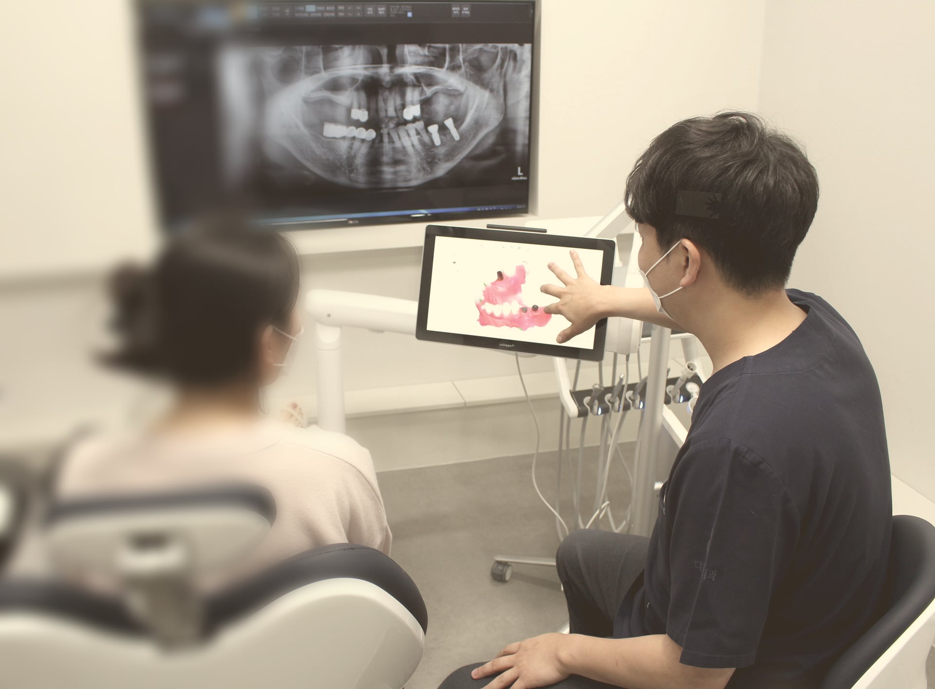 상담실에서 원장이 태블릿 속 치아 사진을 보여 주며 설명하는 모습